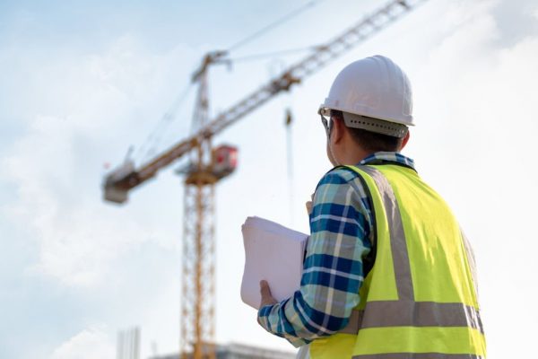 Engineering Consulting people on construction site holding blueprint in his hand and control workflow of the new building.